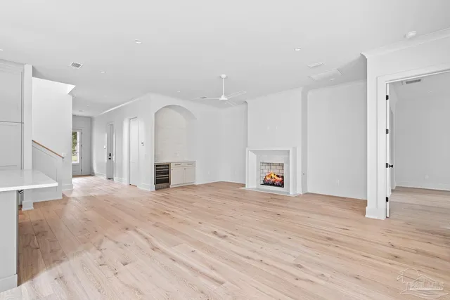 a view of an empty room with wooden floor and a fireplace