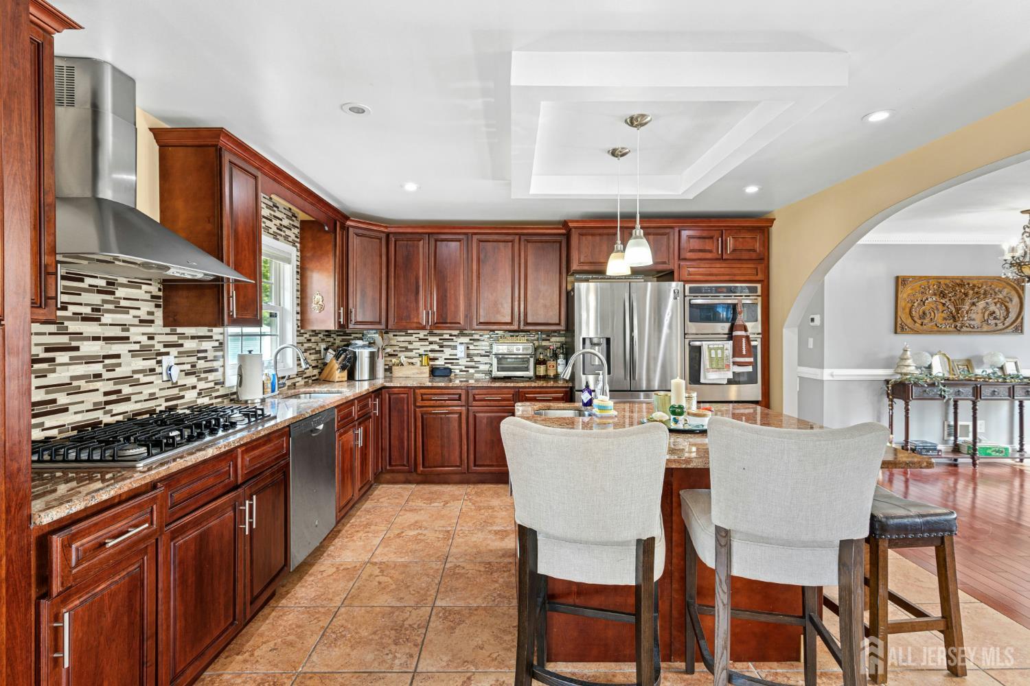 1701 Raritan Road Scotch Plains, NJ 07076 - Photo 22 of 31 a kitchen with stainless steel appliances granite countertop a stove top oven a sink dishwasher a dining table and chairs with wooden cabinets