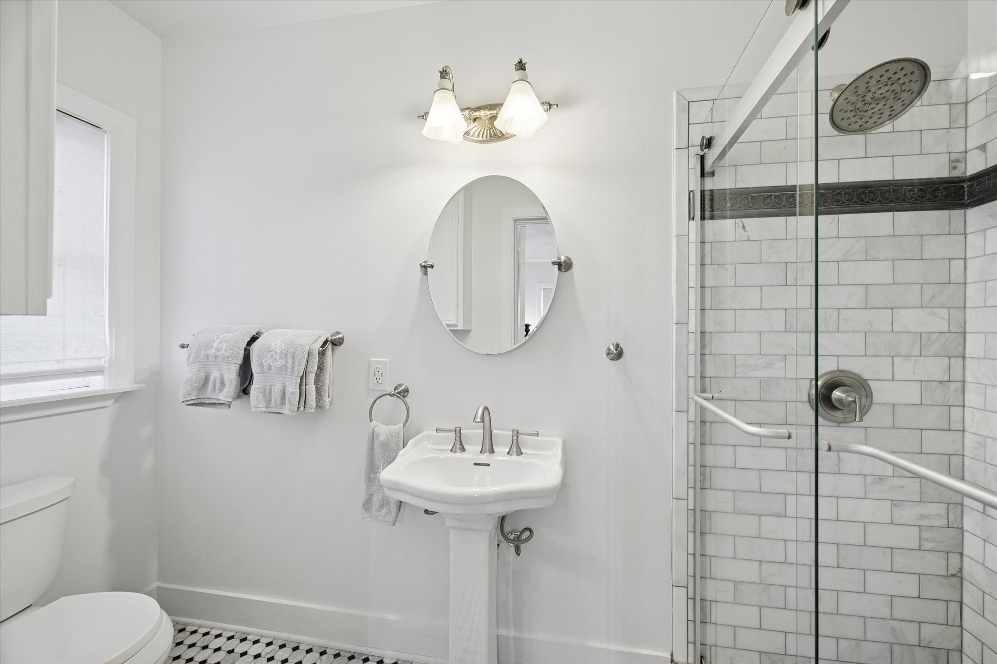 2109 Colquitt Street Houston, TX 77098 - Photo 21 of 28 The secondary bathroom features a pedestal sink, classic finishes, and a walk-in shower with timeless tile detailing.