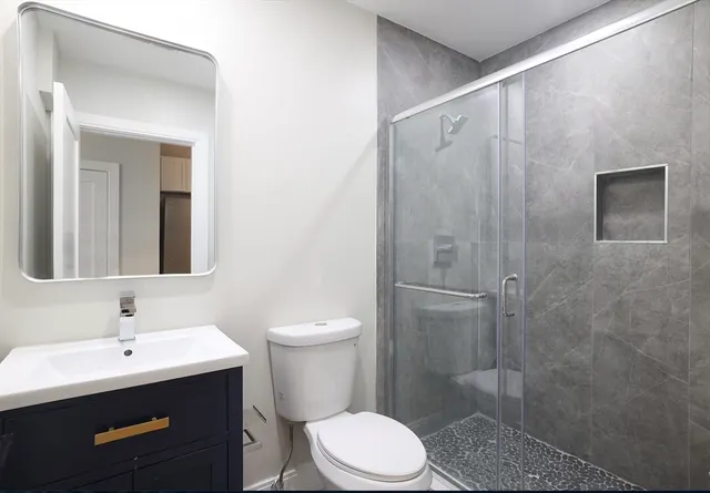 a bathroom with a toilet sink a shower and mirror