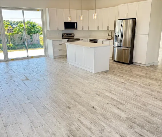 a kitchen with stainless steel appliances a refrigerator a stove a microwave and white cabinets