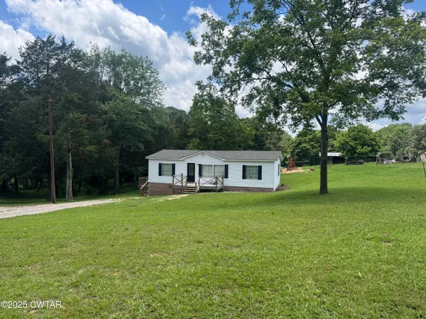 a house that is sitting in the grass with large trees