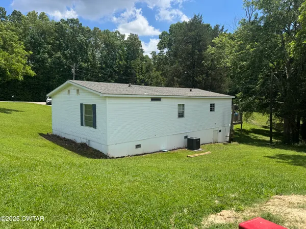 a backyard of a house with plants and large tree