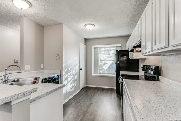 a kitchen with granite countertop a sink stove and cabinets
