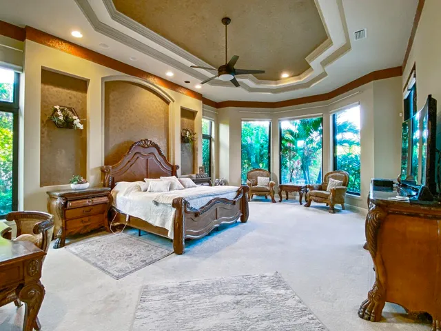 a bedroom with a bed couch and large windows