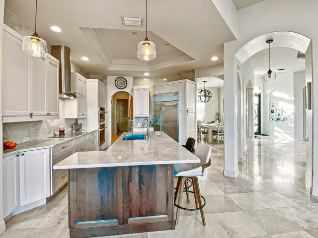 a large kitchen with stainless steel appliances kitchen island granite countertop a table chairs and a refrigerator