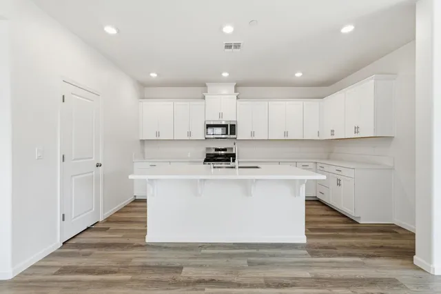 a kitchen with stainless steel appliances granite countertop a white stove top oven and white cabinets