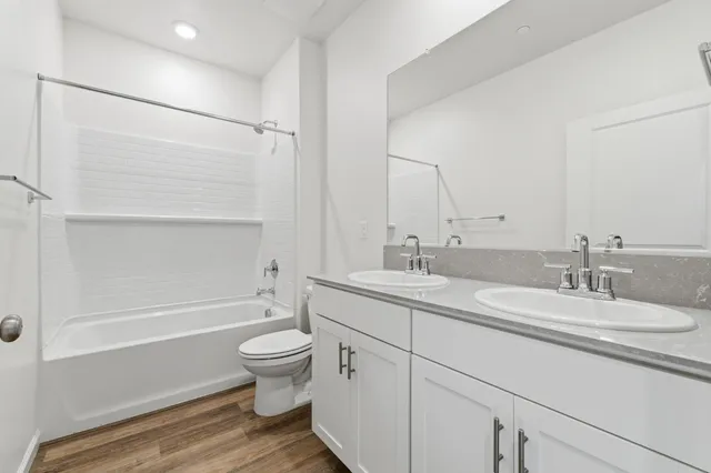 a bathroom with a double vanity sink toilet mirror and shower