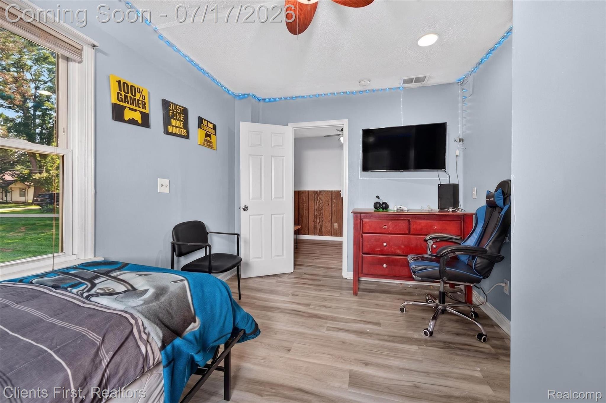 36852 Chase Street Romulus, MI 48174 - Photo 21 of 40 Room featuring light blue walls, wood-finish flooring, a white paneled door, a window with exterior views, and a ceiling fan with light fixture