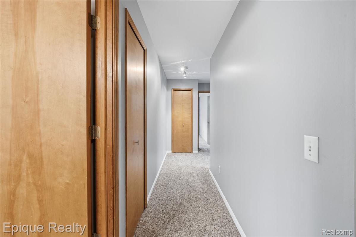 1221 Rhodes Road Lake Orion, MI 48360 - Photo 40 of 72 Carpeted hallway featuring light gray walls, wooden doors, and track lighting fixtures