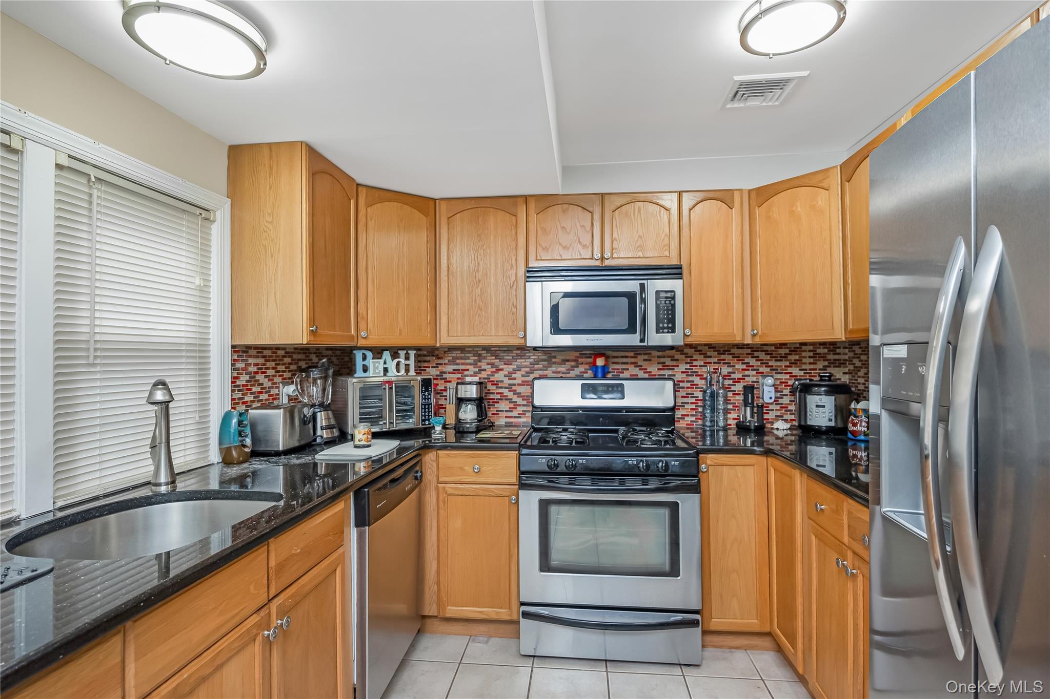 27 June Walk Long Beach, NY 11561 - Photo 12 of 20 a kitchen with stainless steel appliances cabinets a sink and a large window