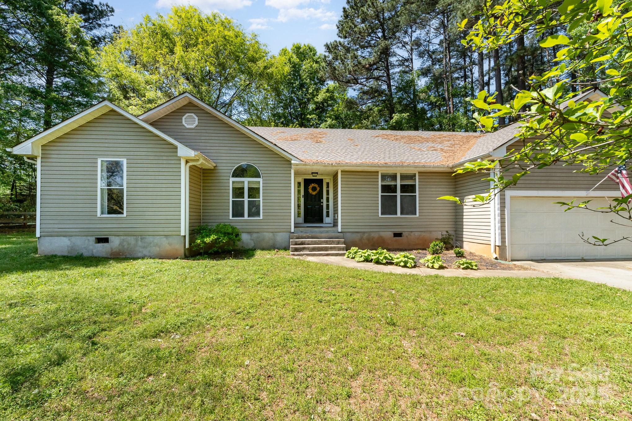 a front view of house with yard and trees in the background
