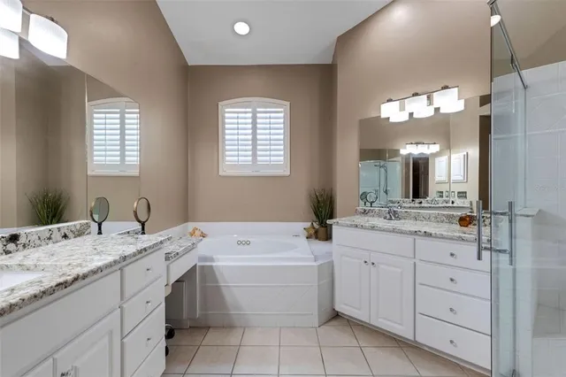 a bathroom with a granite countertop sink mirror bathtub and double