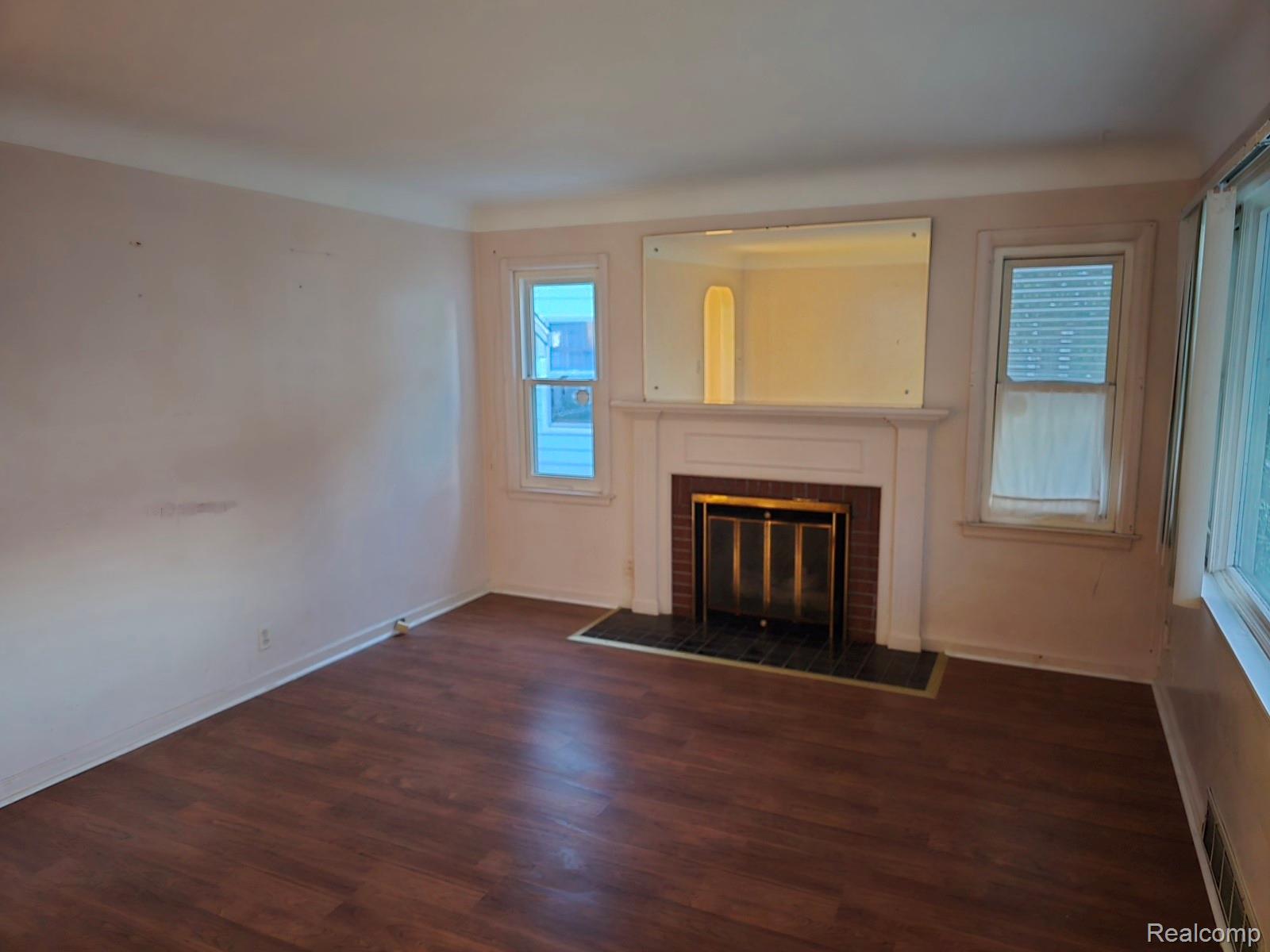 803 Commonwealth Avenue Flint, MI 48503 - Photo 9 of 15 Unfurnished living room featuring dark wood-style floors and a fireplace