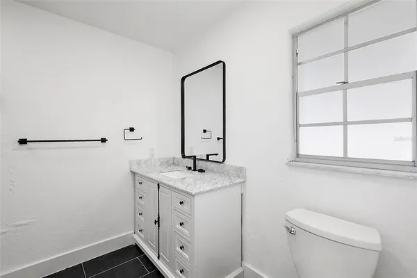 a bathroom with a granite countertop sink a toilet and mirror