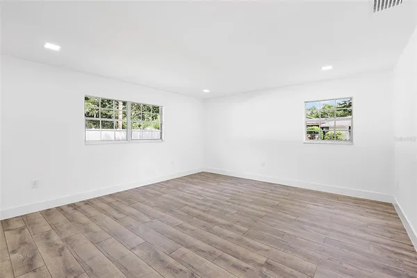 an empty room with wooden floor and window