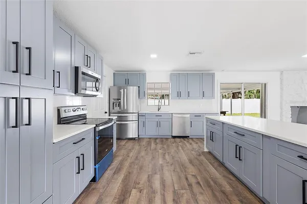 a large kitchen with stainless steel appliances sink a stove and cabinets