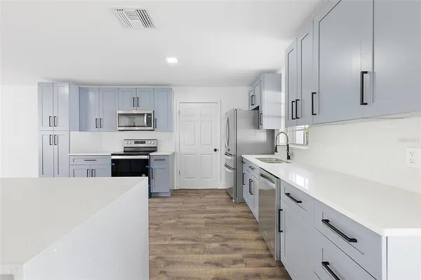 a large kitchen with cabinets wooden floor and stainless steel appliances