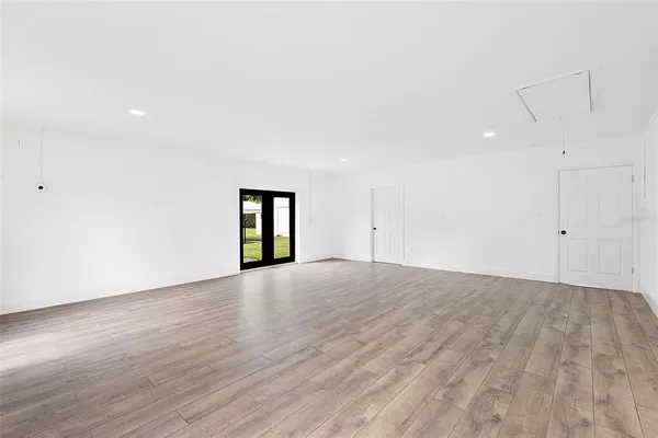 a view of an empty room with wooden floor and window