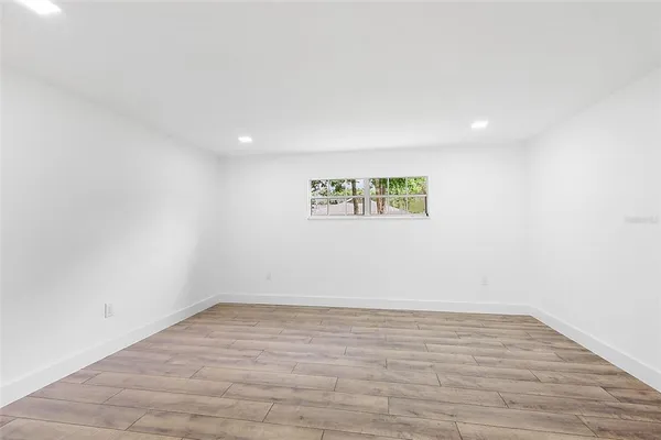 a view of an empty room with wooden floor and a window