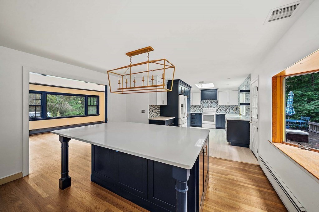 a kitchen with stainless steel appliances kitchen island granite countertop a refrigerator a stove and a wooden floors