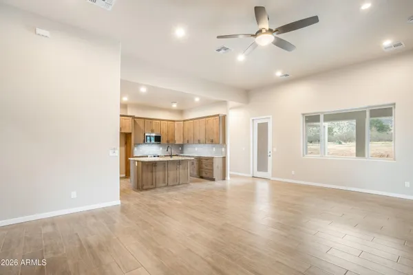 a view of an empty room and kitchen with a ceiling fan