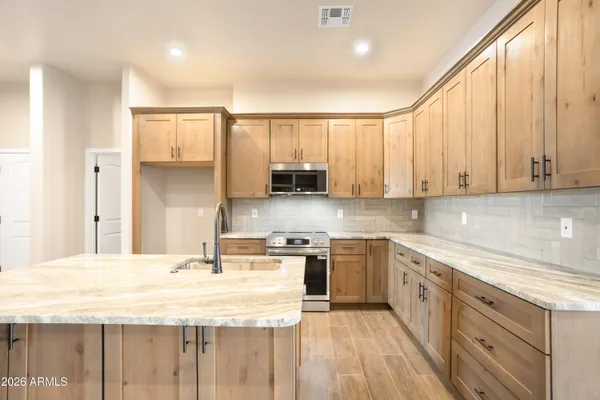 a kitchen that has a sink a microwave oven a stove and white cabinets with wooden floor
