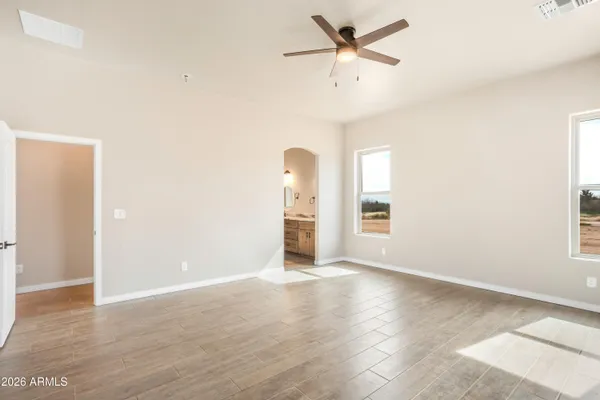an empty room with wooden floor fan and windows