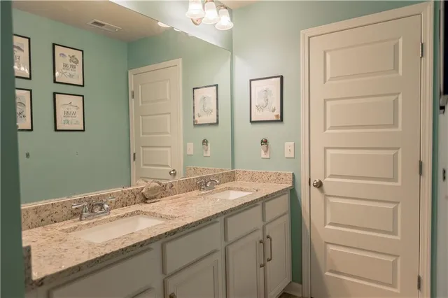 a bathroom with a granite countertop double vanity sink and a mirror