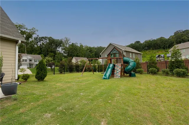 a view of an house with backyard space and slide