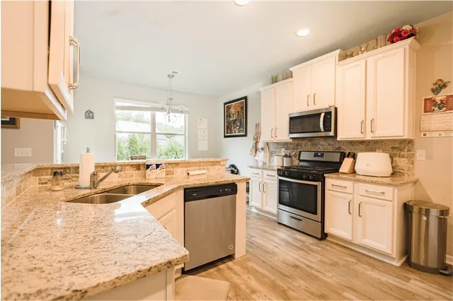 a kitchen with kitchen island granite countertop a sink appliances and cabinets