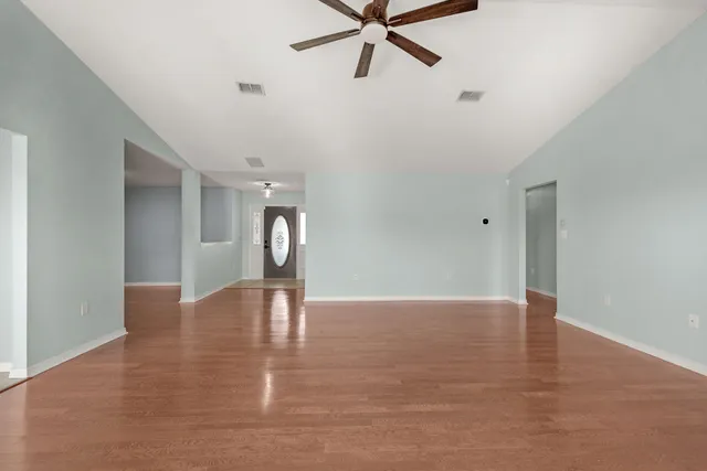 a view of an empty room with window and wooden floor