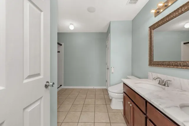 a bathroom with a granite countertop sink a toilet and a mirror