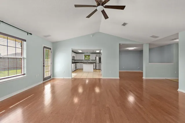 a view of empty room with wooden floor and window