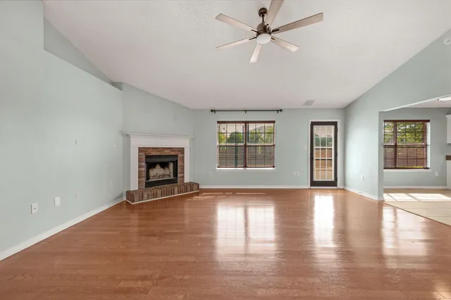 a view of an empty room with window and wooden floor