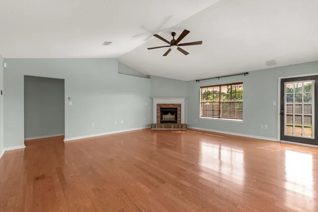 a view of an empty room with a window and wooden floor