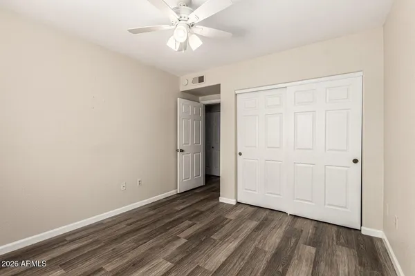 an empty room with wooden floor closet fan and windows