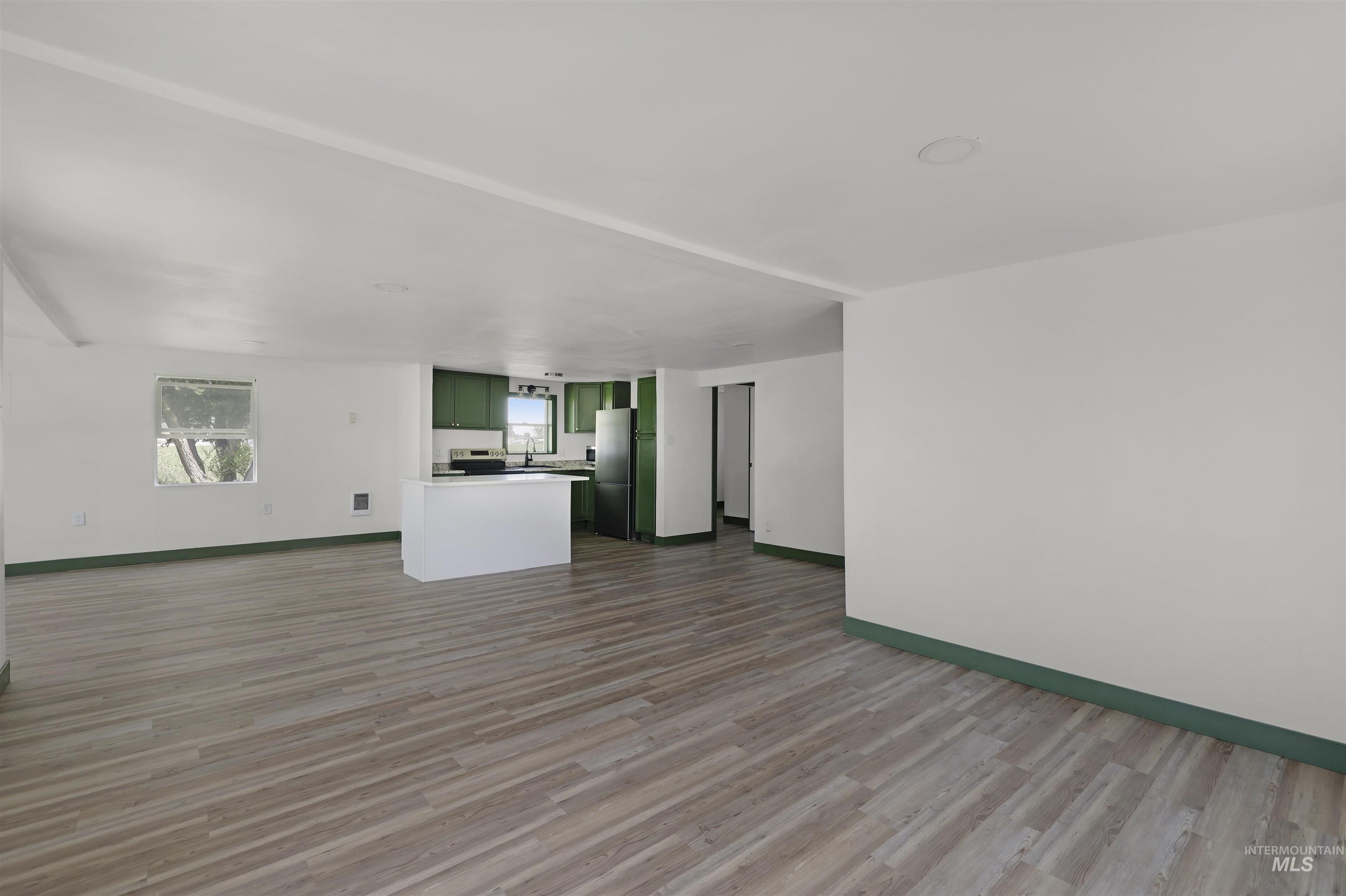 102 South 400 West Rupert, ID 83350 - Photo 2 of 15 Unfurnished living room featuring baseboards and wood finished floors