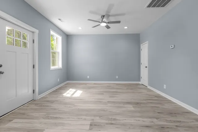 a view of an empty room with window and wooden floor