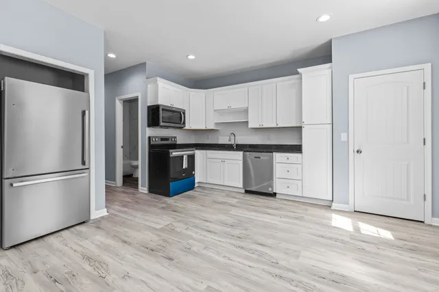 a kitchen with granite countertop a refrigerator and a stove top oven