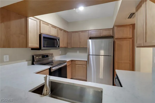 a kitchen with stainless steel appliances granite countertop a refrigerator a stove a microwave oven a sink and dishwasher