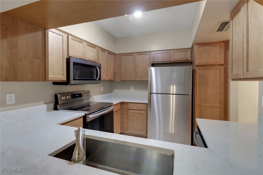 100 Siena Way, Unit 1201 Naples, FL 34119 - Photo 8 of 25 a kitchen with stainless steel appliances granite countertop a refrigerator a stove a microwave oven a sink and dishwasher