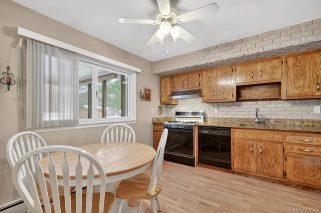 a kitchen with stainless steel appliances granite countertop a stove top oven a sink dishwasher a dining table and chairs with wooden floor