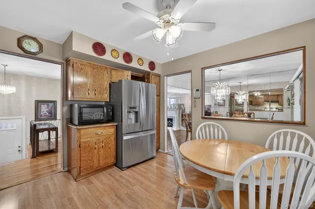 a open kitchen with stainless steel appliances granite countertop a refrigerator a stove top oven and a dining table with wooden floor