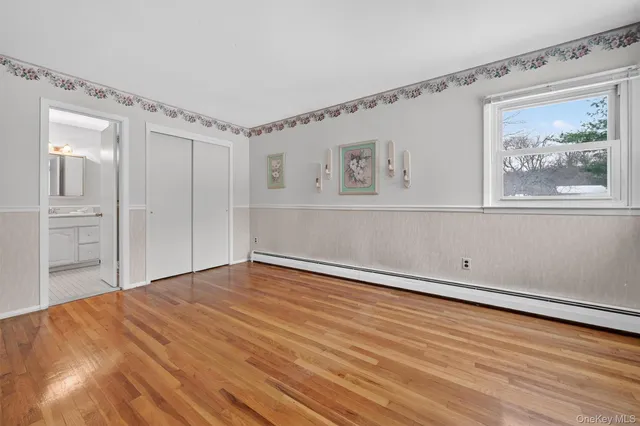 a view of an empty room with window and wooden floor