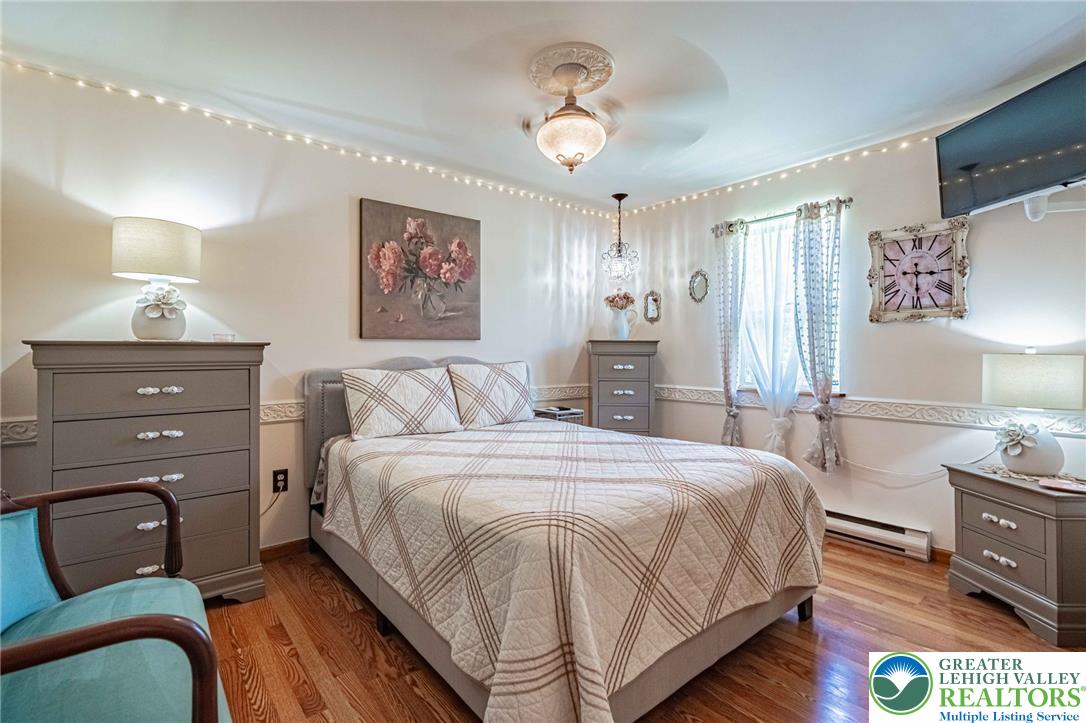 341 Lower Greenhill Road Kunkletown, PA 18058 - Photo 24 of 69 Wood flooring extends throughout this well-lit bedroom, featuring a decorative ceiling fan with a medallion.