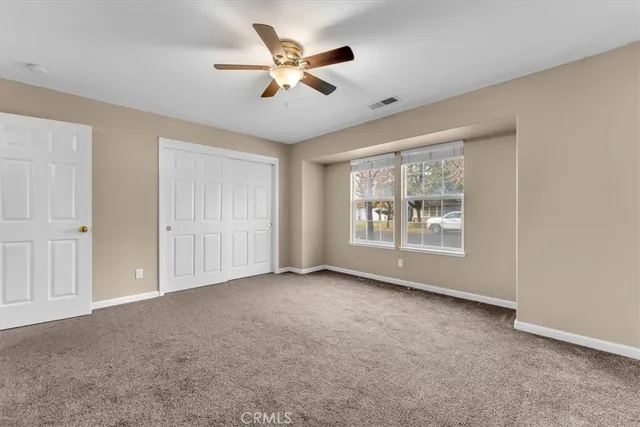 an empty room with windows and chandelier fan