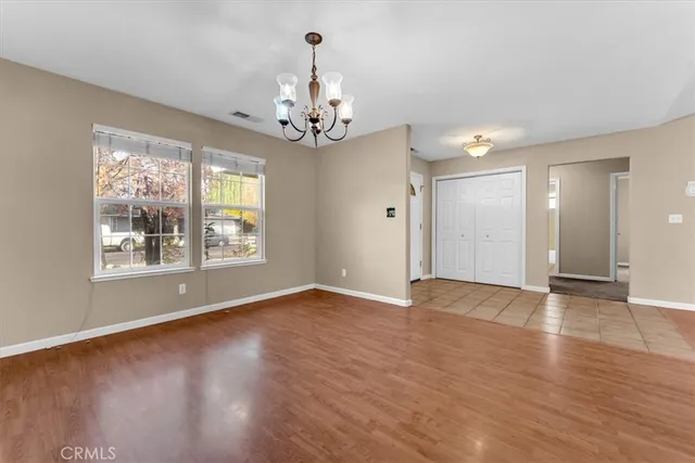 a view of an empty room with wooden floor and a kitchen