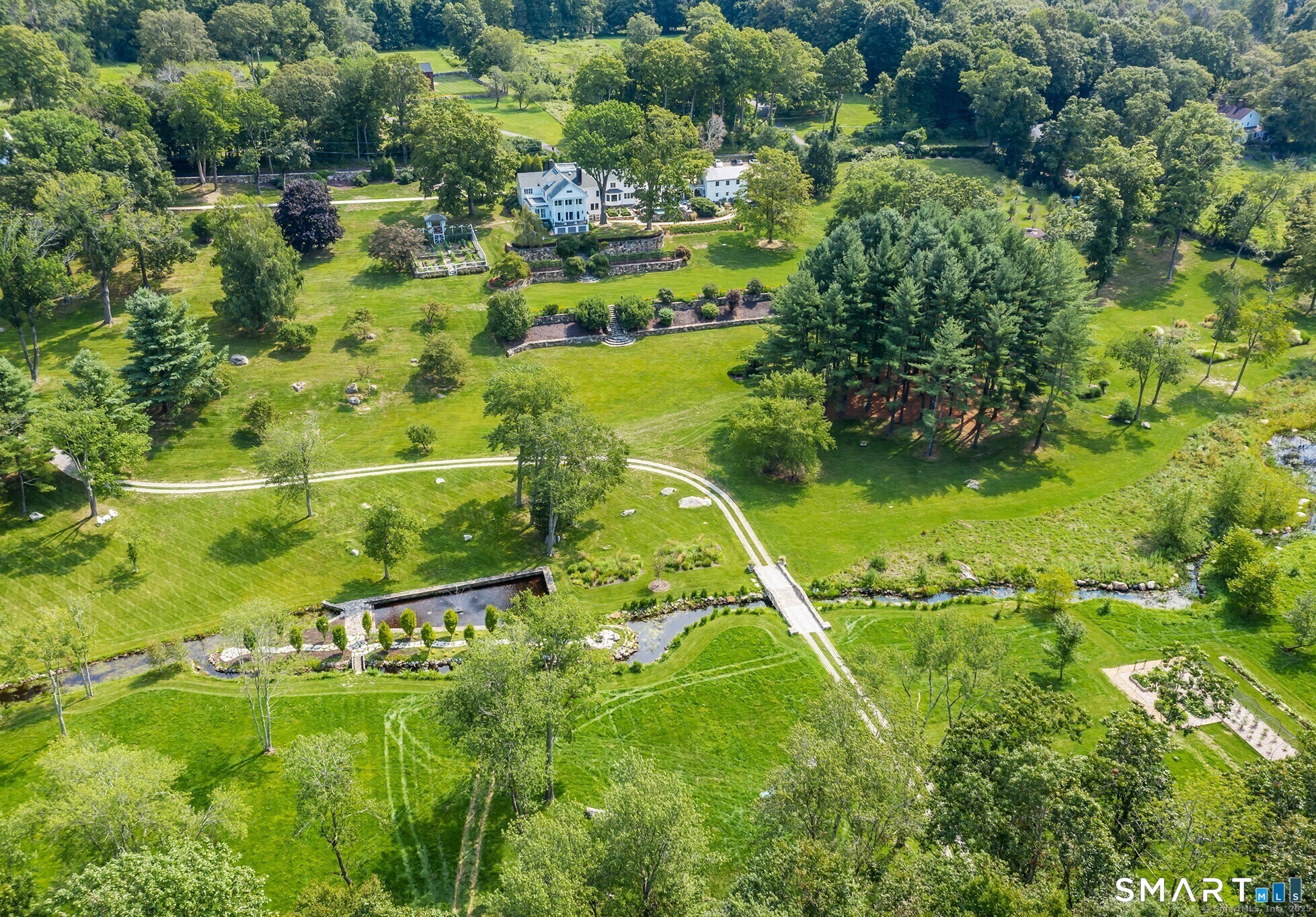 an aerial view of residential houses with outdoor space and trees all around