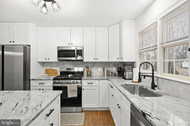 a kitchen with granite countertop white cabinets and stainless steel appliances
